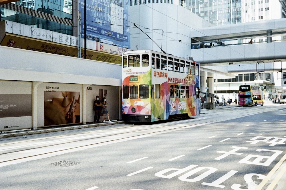 A double-decker Hong Kong tram on a city street with a Stop marking on the road