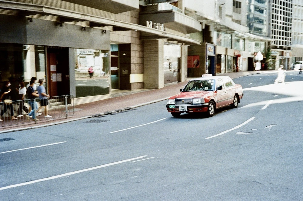 A red Hong Kong taxi on a street in bright sunlight