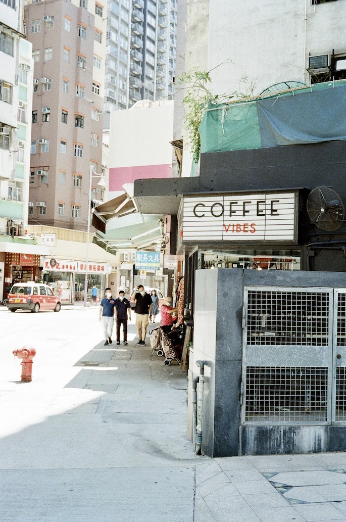 A small coffee shop with a Coffee Vibes sign on a Sheung Wan street corner