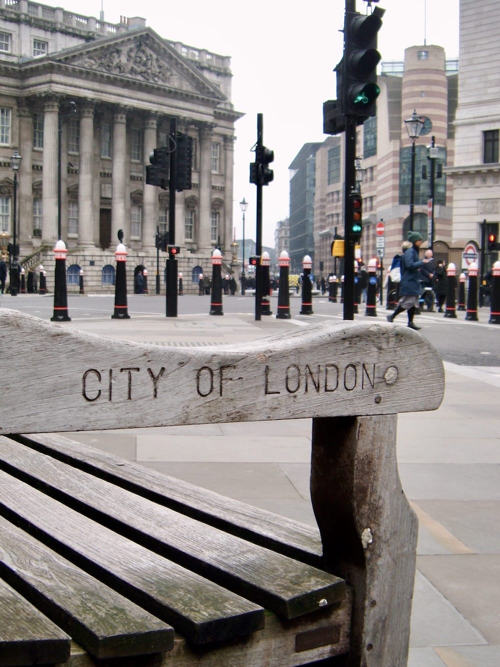 A City of London bench in the foreground with the Bank junction and Mansion House behind