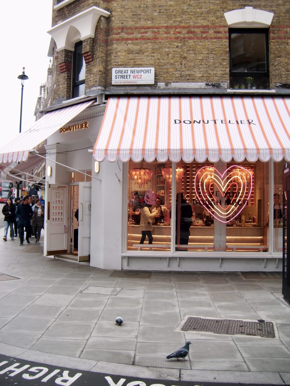 The striped awning and neon heart of the Donutelier shop on the corner of Great Newport Street