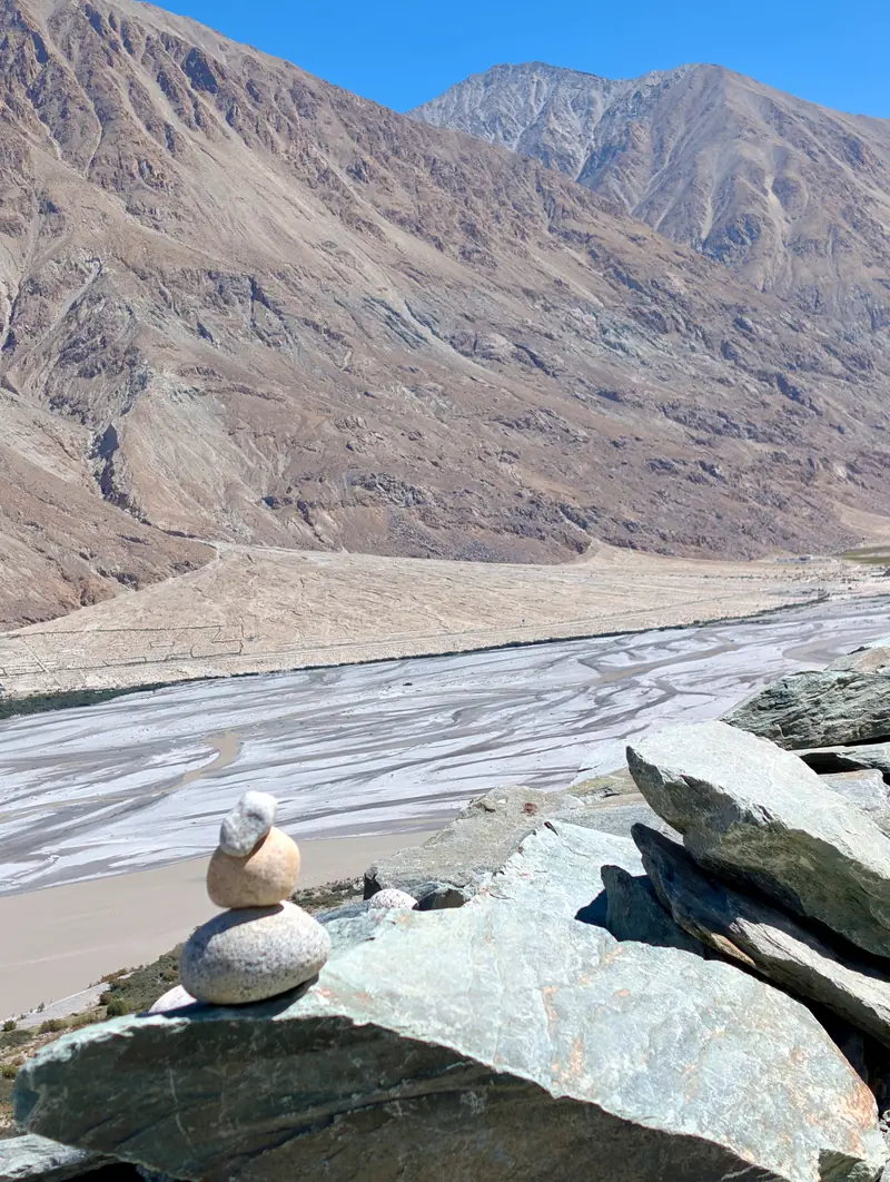A small stone cairn on a boulder above the braided channels of the Nubra river