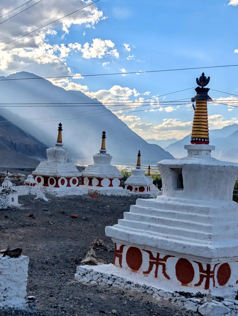 Whitewashed chortens at Diskit with a golden-lit mountain wall behind