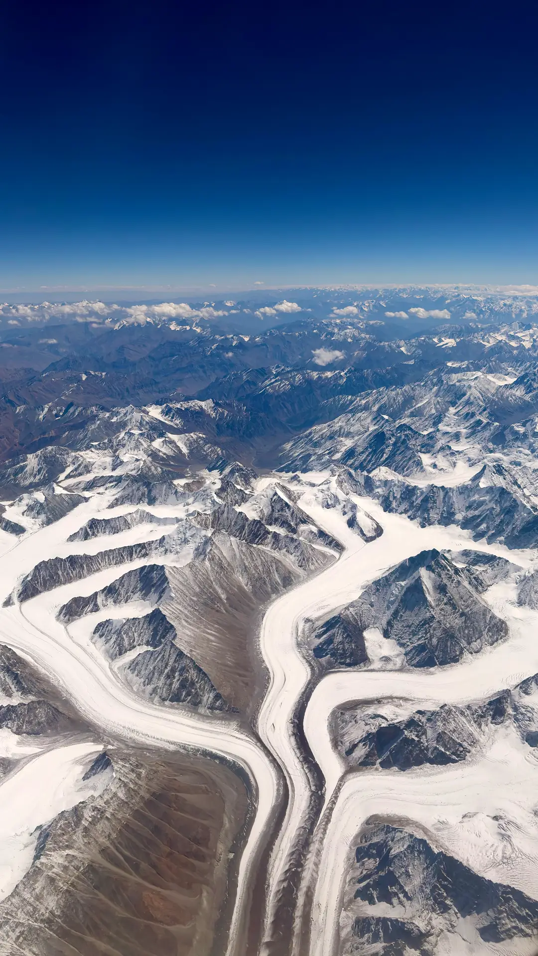 Glaciers converging between snowbound ridges, seen from the aircraft window