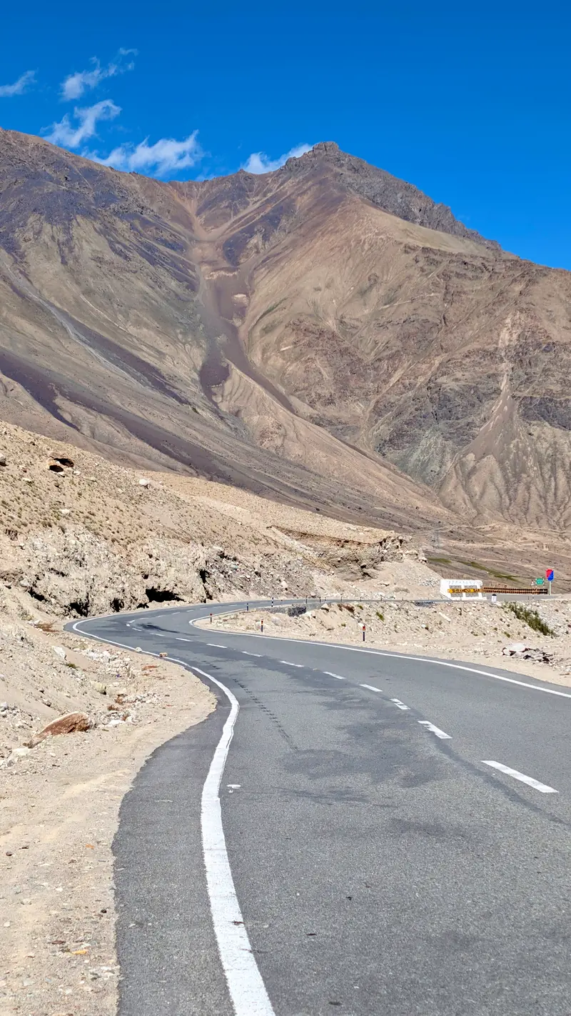 Empty curve of tarmac descending the north side of Khardung La between bare mountains