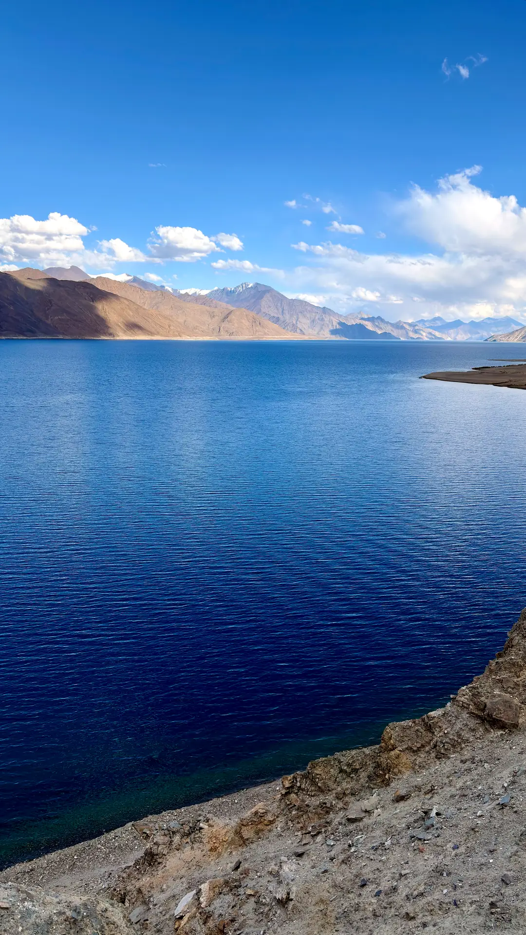 Pangong Tso stretching to the horizon in bands of deep blue
