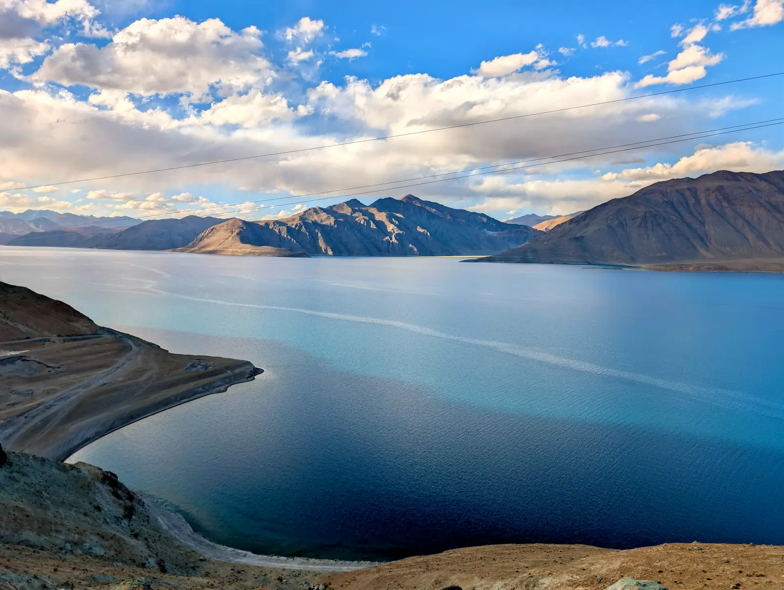 Pangong Tso at evening, the water flat and pale, mountains doubled in reflection