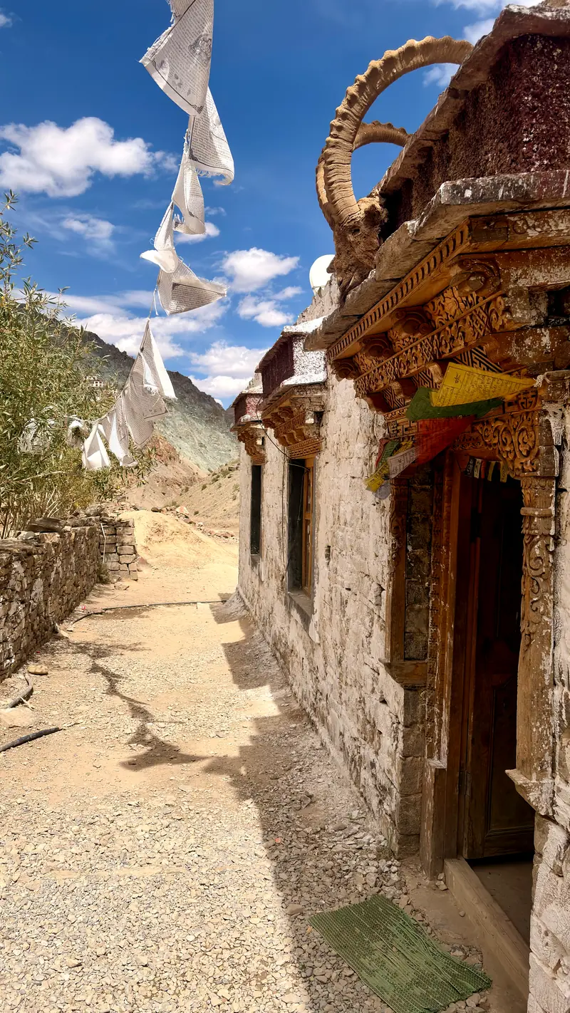 Ibex horns mounted above a monastery doorway, prayer flags streaming overhead