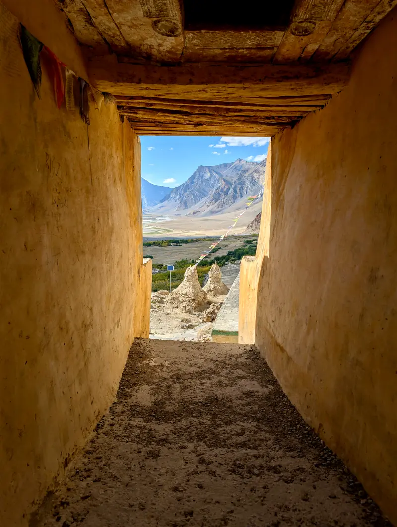 A mud-walled corridor opening onto chortens and mountains