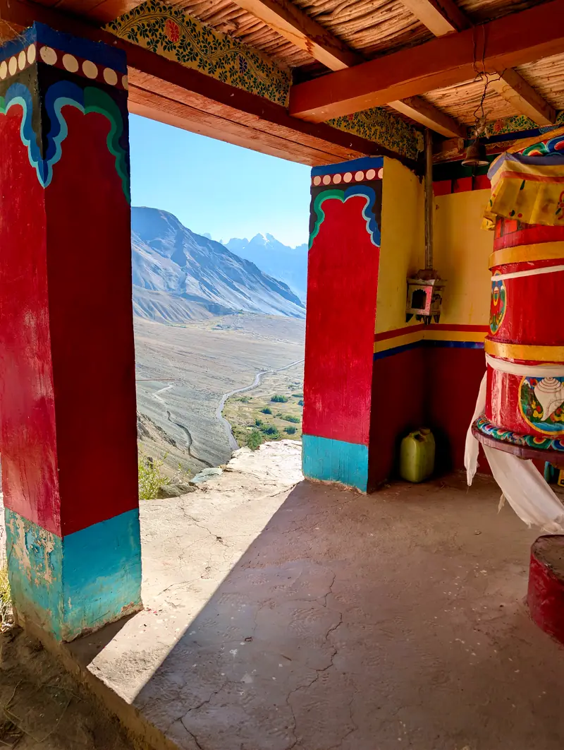 A large painted prayer wheel on a porch overlooking the valley
