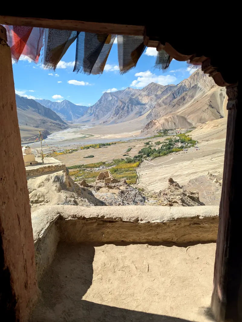 A view through an old timber window frame across the wide valley floor