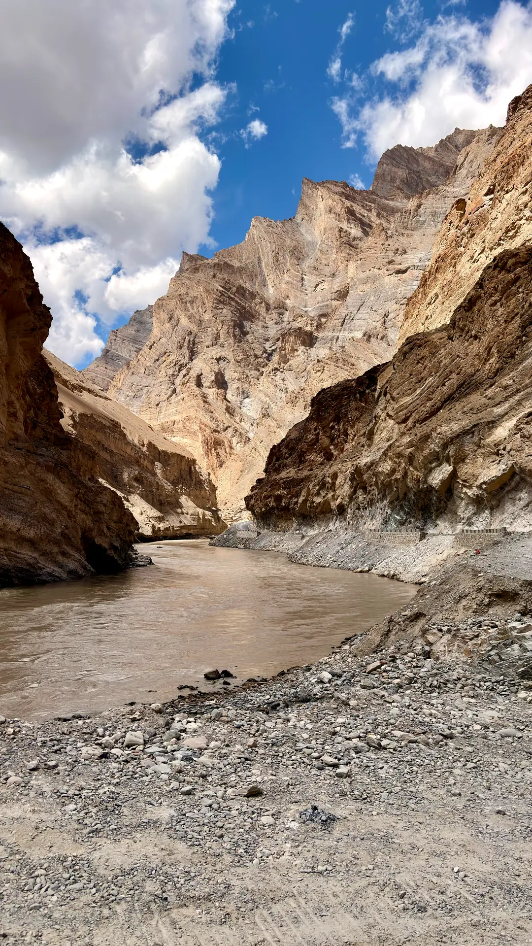 The silt-brown Zanskar river running through a sheer rock gorge under broken clouds